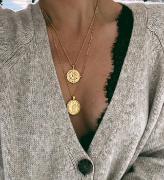 18k gold plated two coin necklaces one shorter than the other. worn by a model wearing a grey knot cardigan, v neck at front with black lace trim on bra showing. Coins Layered Necklaces - Gold Lunar