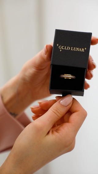 Cubic Zirconia Halo Ring - Gold Lunar shown in gift box with a model opening the drawer of the gift box. tattoo on wrist of the model and pale pink gel nails.