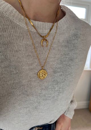 model wearing a cream knit jumper and blue wide leg jeans from Zara with a gold plated crescent moon shaped pendant necklace on a snake chain and a longer gold coin necklace on a fine ball chain.