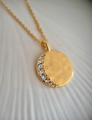 18k gold plated celestial moon disc with Cubic Zirconia stones in a crescent moon shape on a hammered molten disc on fine chain necklace