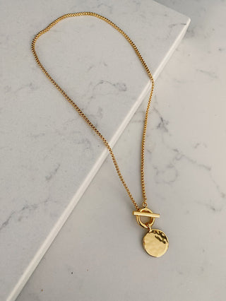 gold plated T Bar & Disc Necklace - Gold Lunar displayed on a marble quartz worktop