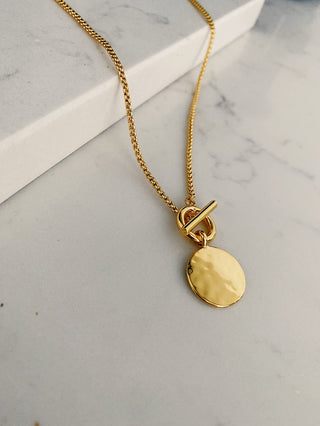 gold plated T Bar & Disc Necklace - Gold Lunar displayed on a marble quartz worktop