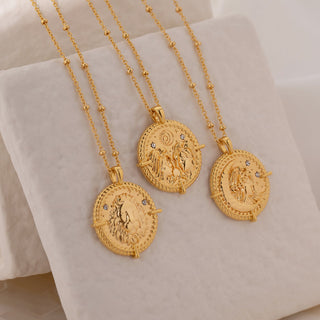 Gemini, Leo and Virgo disc pendant Necklaces on fine ball chain laid against a concrete tile