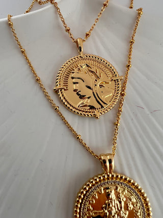 18k gold plated two coin necklaces one shorter than the other displayed on ceramic dish.