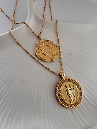 18k gold plated two coin necklaces one shorter than the other. displayed on ceramic dish.