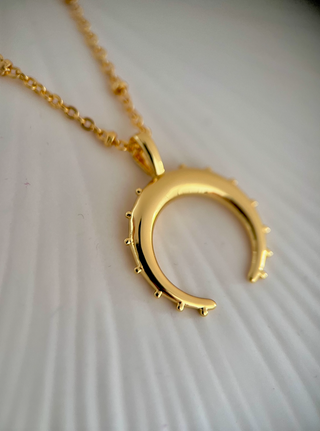 18k gold plated crescent moon necklace on fine ball chain on a jewellery dish