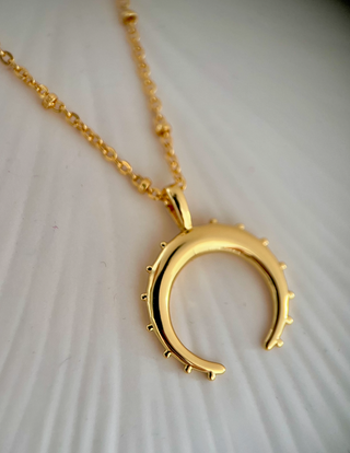 18k gold plated crescent moon necklace on fine ball chain on a jewellery dish