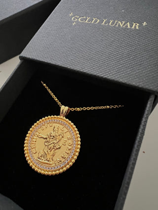 18k gold plated coin pendant necklace with cubic zirconia gemstones around the outside on a fine gold chain displayed inside a gold lunar gift box which is black with a velvet insert and gold branding on the front of the gift box