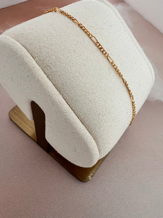 18k gold plated Fine Casual Chain on a cream cushion bracelet stand with a gold base