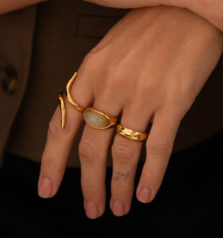 Three 8k gold plated rings worn across fingers on a model wearing a Zara brown waistcoat. one sleek ring, one new Jade gemstone ring and one band ring.