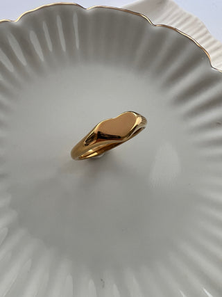 gold plated heart band ring shown on pretty white dish