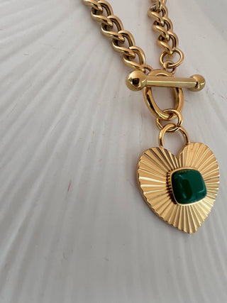 Close up photo of the Green agate heart necklace in 18k gold plated on chunky curb link chain showing the T bar function displayed on a white jewellery dish