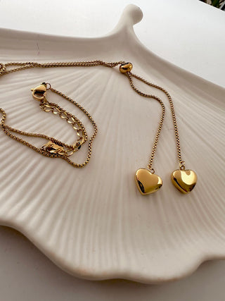 gold plated heart lariat necklace displayed on a dressing table white jewellery dish 