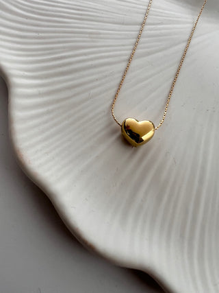 18k gold plated heart necklace on very fine chain short necklace displayed on a pretty white dish for jewellery