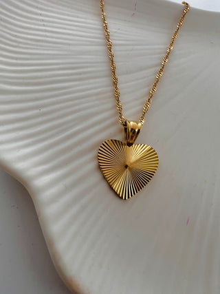 gold heart pendant on a twist rope chain displayed on a white pretty jewellery dish