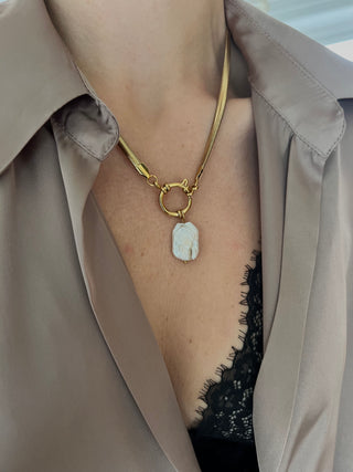 gold plated herringbone chain with a large round clasp and a large freshwater rectangular shaped pearl chain worn on a model wearing a brown Zara silky shirt exposing black lace bra