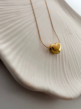 18k gold plated bubble heart necklace on a fine chain displayed on a pretty white dish