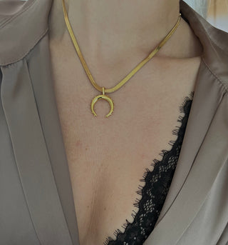 18k gold plated crescent moon pendant on a fine snake chain worn by a model wearing a Zara brown silky shirt open at the front with exposed black lace bra