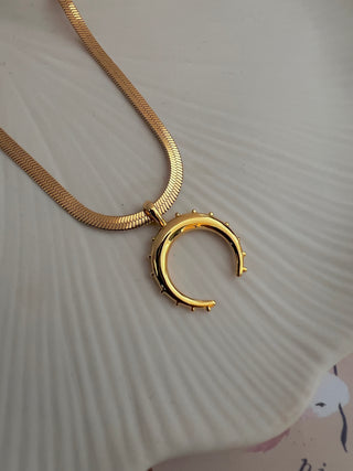 18k gold plated crescent moon pendant on a fine snake chain displayed on a white ceramic plate