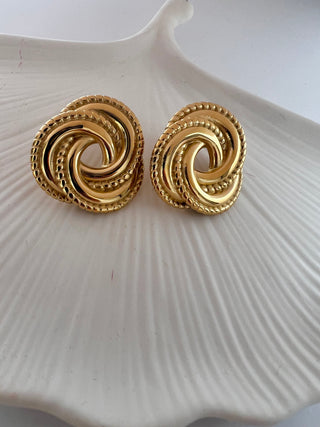 gold plated oversized twist stud earrings on white ceramic dish