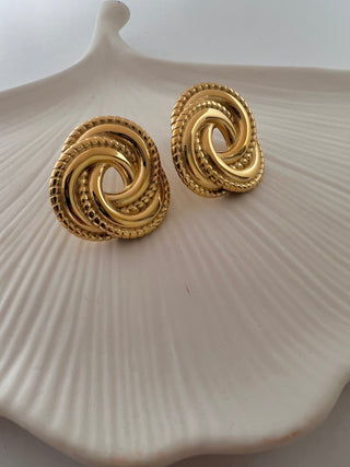 gold plated oversized twist stud earrings on white ceramic dish