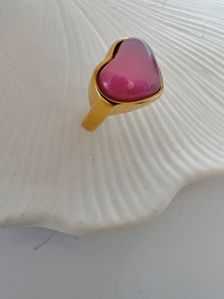 pink cats eye puffy heart ring in gold displayed on a white jewellery dish