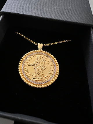 18k gold plated coin pendant necklace with cubic zirconia gemstones around the outside on a fine gold chain displayed inside a gold lunar gift box which is black with a velvet insert and gold branding on the front of the gift box