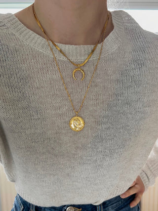 gold snake chain with crescent moon pendant with a longer necklace on fine ball chain with a coin pendant worn by model wearing a cream knit jumper from Zara and blue high waist wide jeans from Zara. 