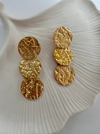 Triple hammered 18k gold plated disc drop earrings displayed on a white jewellery dish