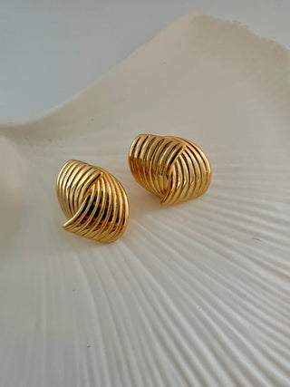 18k gold plated wrap over stud earrings with ribbed detailing displayed on a white jewellery ceramic dish